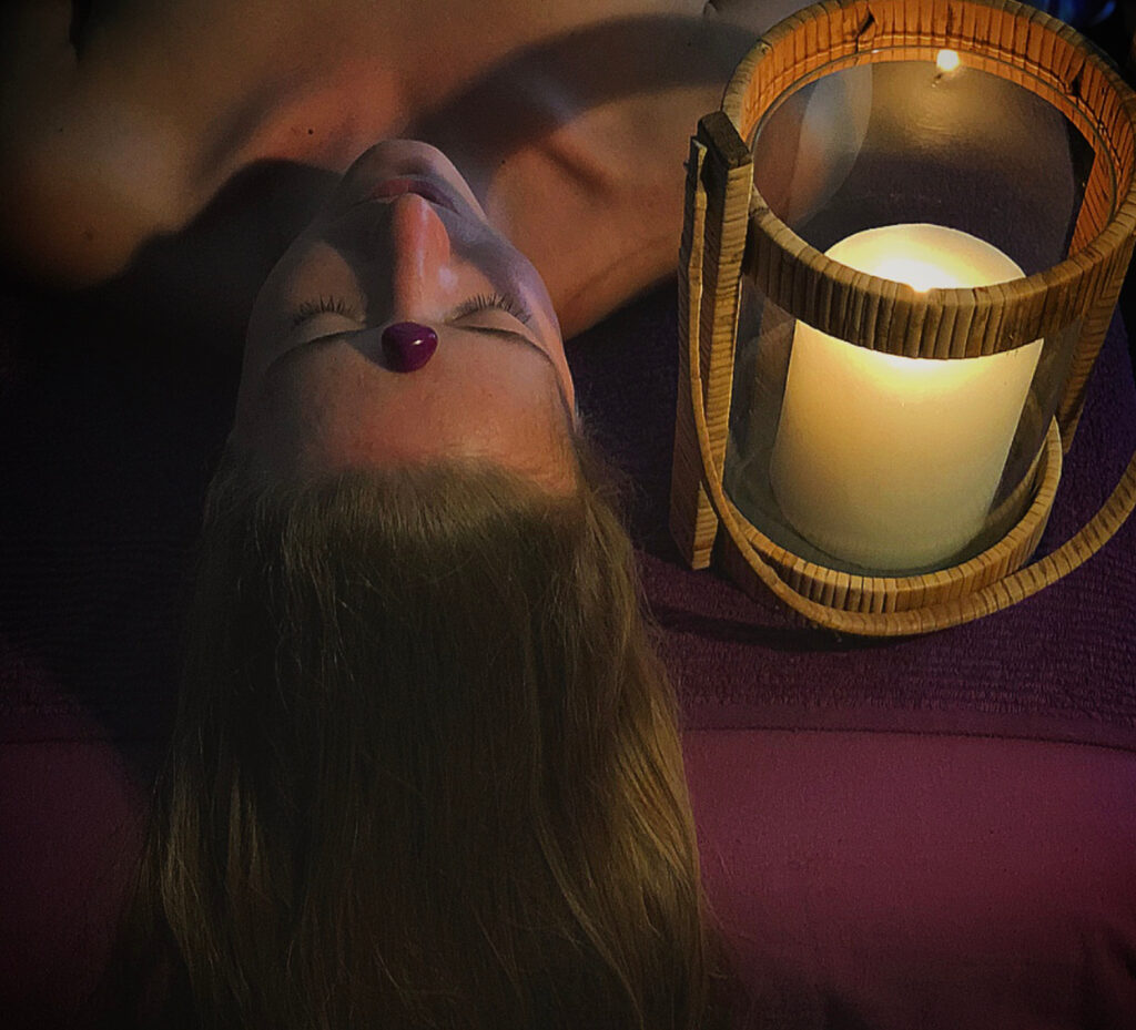 Femme allongée dans la pénombre sur une table de massage avec une bougie